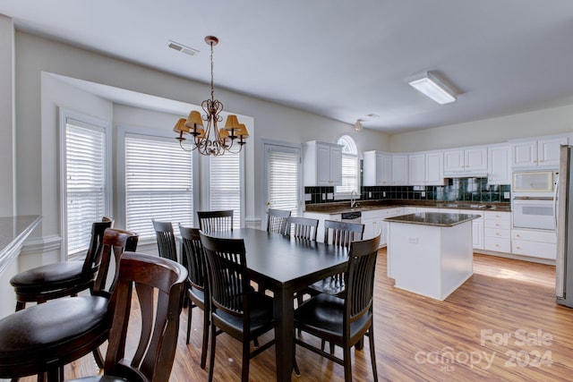 dining area with sink, a chandelier, and light hardwood / wood-style floors