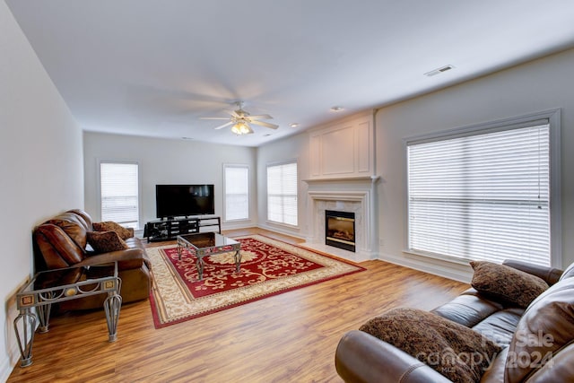 living room featuring light hardwood / wood-style flooring, a fireplace, and ceiling fan