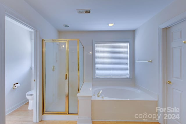 bathroom featuring toilet, hardwood / wood-style flooring, and separate shower and tub