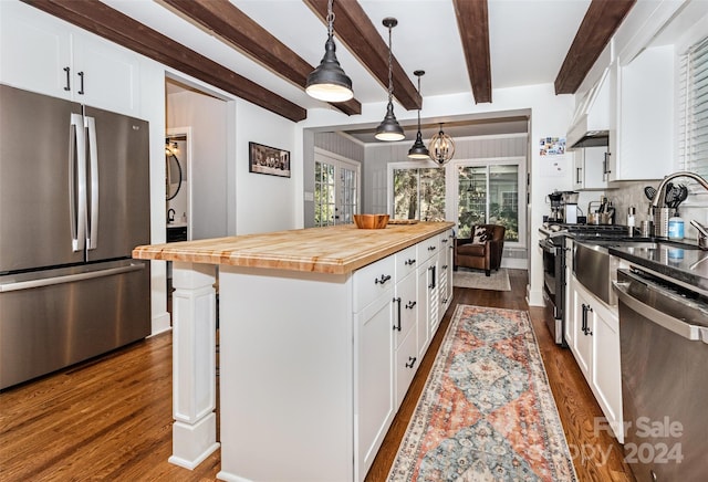 kitchen with butcher block counters, a center island, white cabinets, hanging light fixtures, and appliances with stainless steel finishes