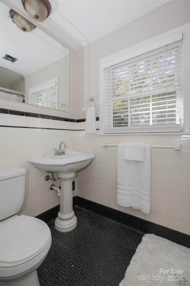 bathroom with tile patterned flooring, toilet, and tile walls