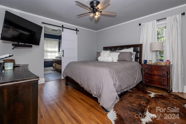 bedroom featuring multiple windows, a barn door, dark hardwood / wood-style floors, and ceiling fan