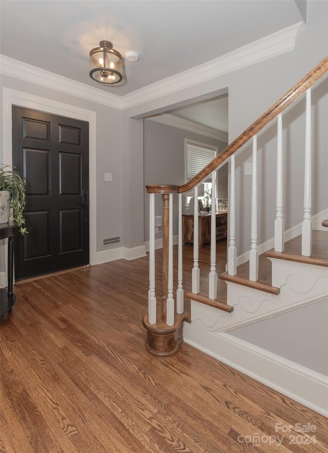 foyer with wood-type flooring, crown molding, and a notable chandelier