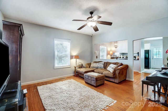 living room featuring a textured ceiling, light hardwood / wood-style flooring, and ceiling fan