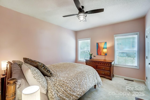 bedroom with multiple windows, light colored carpet, and ceiling fan