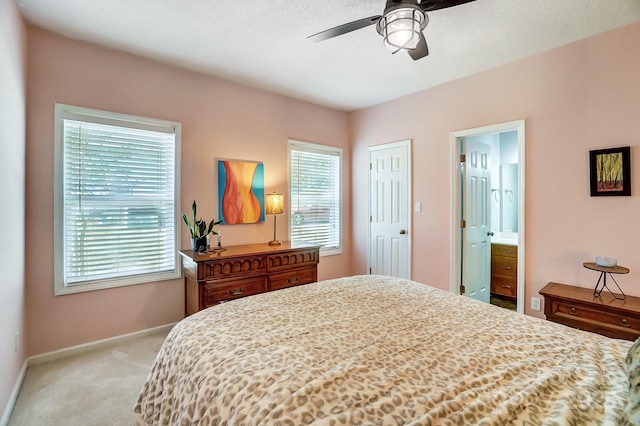 bedroom featuring connected bathroom, light colored carpet, and ceiling fan