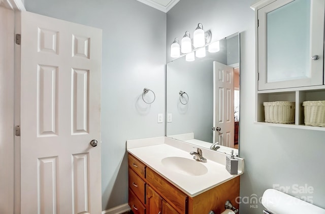 bathroom with vanity, toilet, and ornamental molding