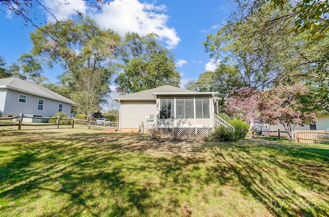 rear view of property featuring a yard and a sunroom