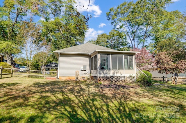 view of home's exterior with a sunroom and a yard