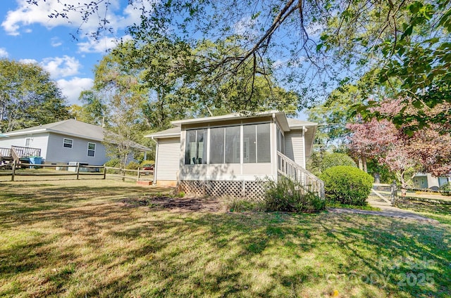 back of property with a lawn and a sunroom