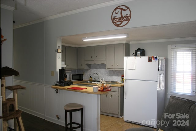 316 N Government St, Lincolnton, NC 28092 - kitchen with kitchen peninsula, ornamental molding, sink, a kitchen bar, and white refrigerator