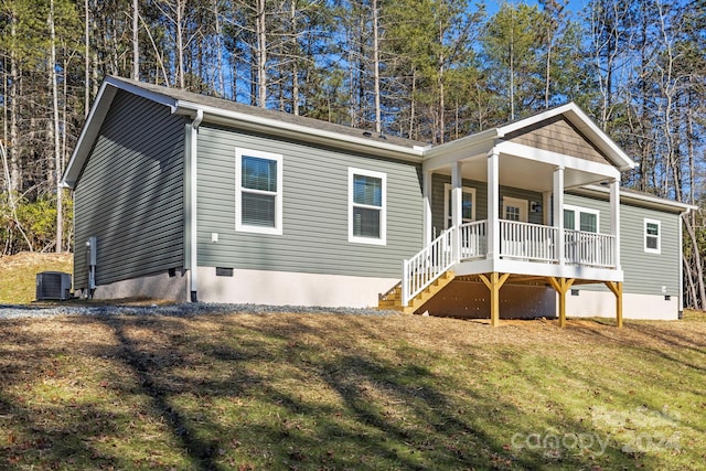 back of property with covered porch, central air condition unit, and a lawn