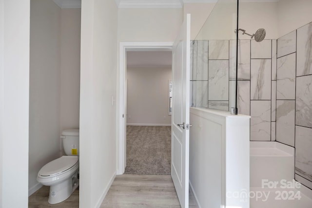 bathroom with a shower, hardwood / wood-style floors, toilet, and ornamental molding