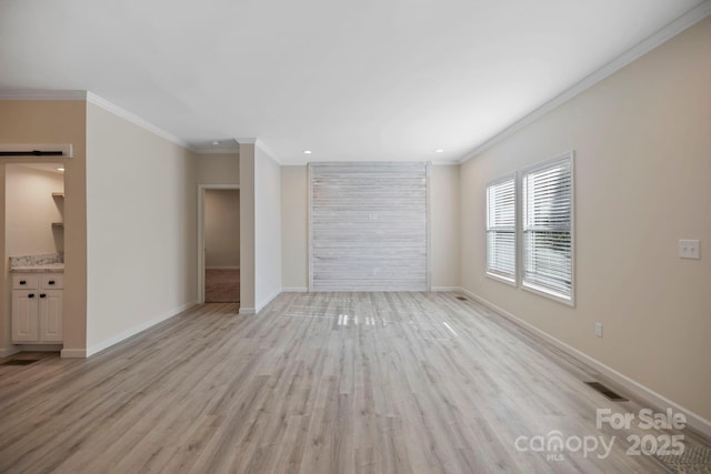 unfurnished room with light wood-style floors, a barn door, visible vents, and baseboards