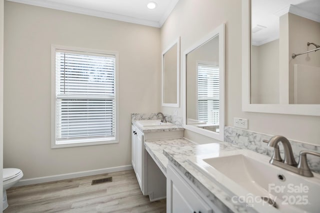 bathroom with baseboards, visible vents, wood finished floors, crown molding, and vanity