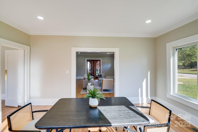 dining area featuring a wealth of natural light, ornamental molding, and light hardwood / wood-style flooring