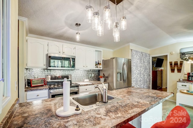 kitchen with sink, vaulted ceiling, pendant lighting, white cabinetry, and appliances with stainless steel finishes