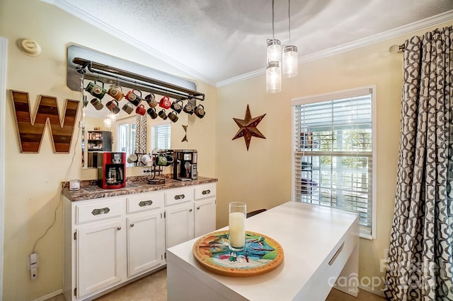 kitchen with a wealth of natural light, ornamental molding, white cabinetry, and decorative light fixtures