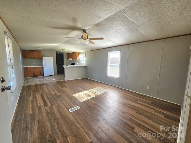 unfurnished living room featuring dark wood-type flooring, ceiling fan, a textured ceiling, and vaulted ceiling