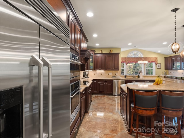 kitchen featuring appliances with stainless steel finishes, backsplash, light stone counters, decorative light fixtures, and an inviting chandelier