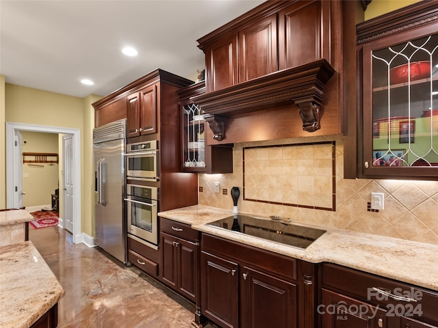 kitchen with light stone countertops, dark brown cabinets, stainless steel appliances, and tasteful backsplash