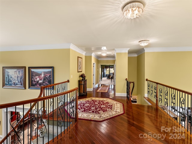 hallway featuring hardwood / wood-style flooring, decorative columns, ornamental molding, and a chandelier