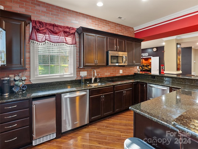 kitchen with sink, crown molding, light hardwood / wood-style floors, dark brown cabinets, and appliances with stainless steel finishes