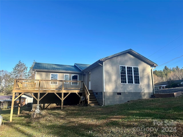 back of property featuring a deck and a lawn