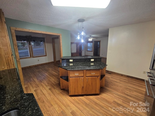 kitchen featuring hanging light fixtures, a textured ceiling, and light hardwood / wood-style flooring