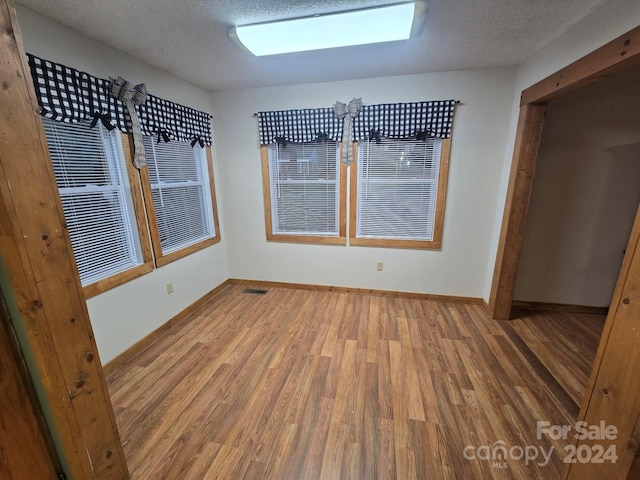 empty room featuring a textured ceiling and hardwood / wood-style flooring