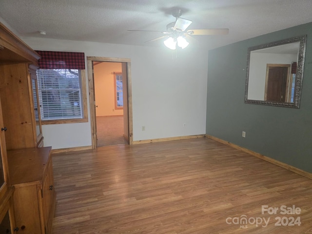 empty room featuring ceiling fan, a textured ceiling, and light wood-type flooring