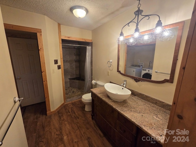 bathroom with sink, a textured ceiling, curtained shower, hardwood / wood-style floors, and washing machine and dryer