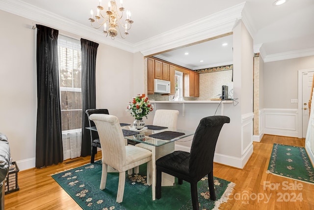 dining space featuring crown molding, a chandelier, and light wood-type flooring