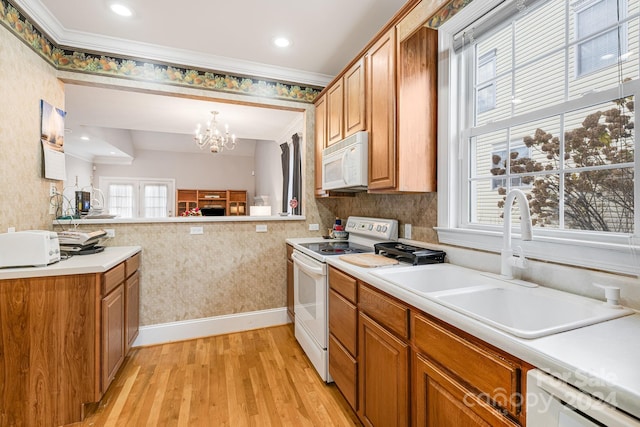 kitchen with crown molding, light hardwood / wood-style floors, a notable chandelier, sink, and white appliances