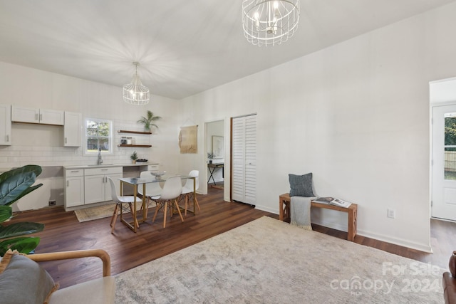 dining room with a wealth of natural light, sink, dark wood-type flooring, and an inviting chandelier