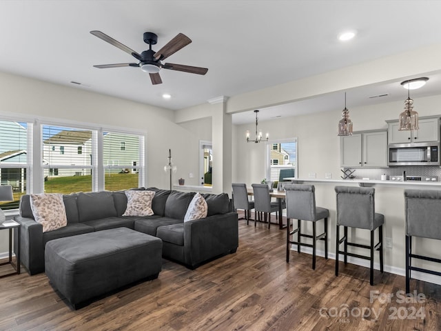 living room with ceiling fan with notable chandelier and dark hardwood / wood-style flooring