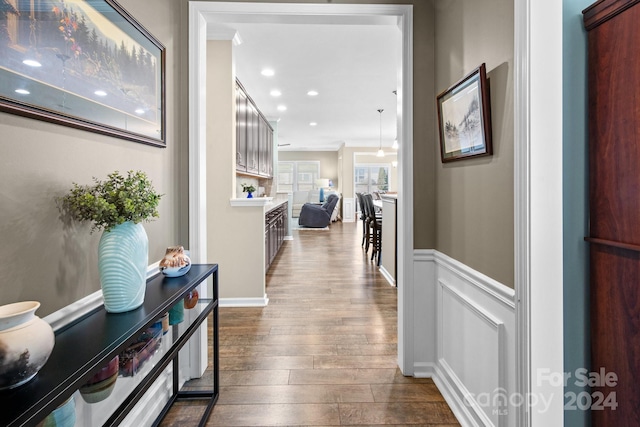 corridor featuring wood-type flooring and ornamental molding