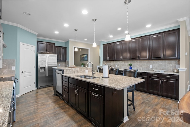 kitchen featuring dark wood-type flooring, an island with sink, stainless steel appliances, sink, and pendant lighting