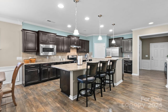 kitchen with dark hardwood / wood-style floors, stainless steel appliances, a center island with sink, and pendant lighting