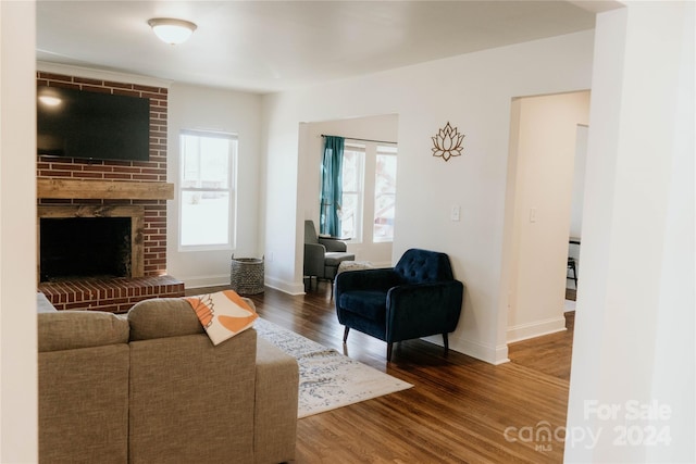 living room with a brick fireplace and dark hardwood / wood-style flooring