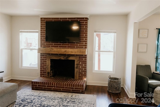 living room featuring dark hardwood / wood-style flooring, a healthy amount of sunlight, and a brick fireplace