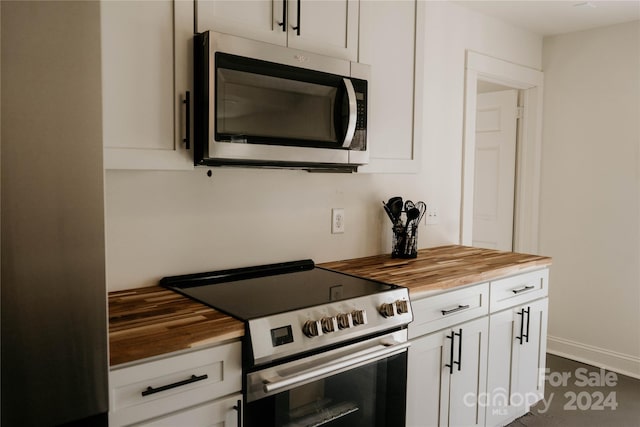 kitchen with white cabinets, butcher block countertops, and appliances with stainless steel finishes