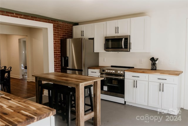 kitchen with butcher block counters, dark hardwood / wood-style floors, white cabinetry, and appliances with stainless steel finishes