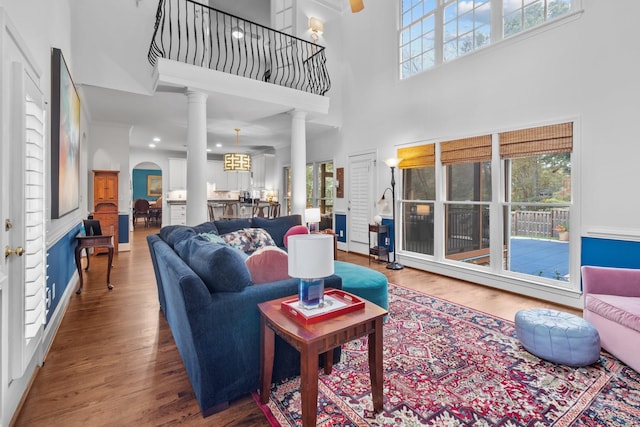 living room with a wealth of natural light, wood-type flooring, and a high ceiling