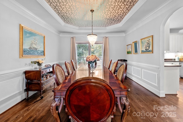 dining area featuring a raised ceiling, crown molding, dark hardwood / wood-style floors, and an inviting chandelier