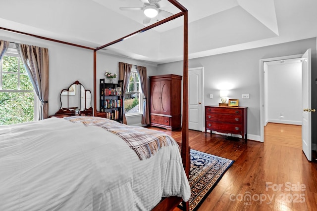 bedroom with ceiling fan, a tray ceiling, and multiple windows