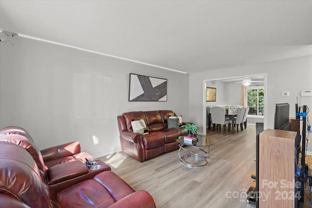 living room featuring light hardwood / wood-style flooring, lofted ceiling, and ceiling fan