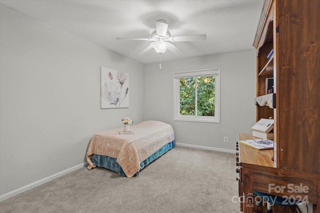 bedroom with ceiling fan, carpet flooring, and a textured ceiling