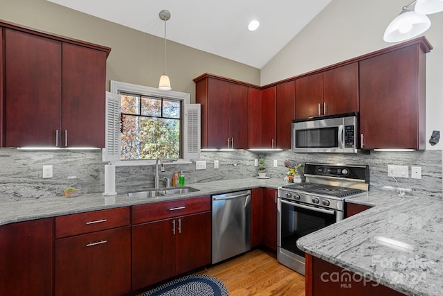 kitchen featuring lofted ceiling, tasteful backsplash, light stone countertops, sink, and stainless steel appliances