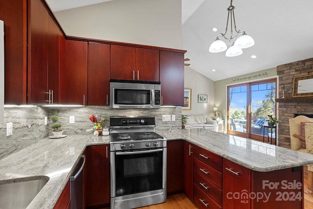 kitchen with tasteful backsplash, appliances with stainless steel finishes, lofted ceiling, and kitchen peninsula